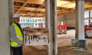 Ein Mann mit Schutzhelm hält ein Foto auf einer Baustelle