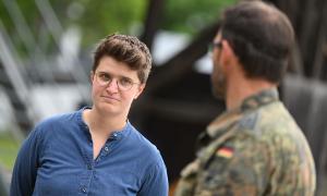 Eine Frau mit Brille, im Vordergrund leicht verschwommen ein Soldat