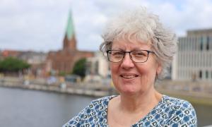 Eine Frau, im Hintergrund ein Ufer und eine Kirche
