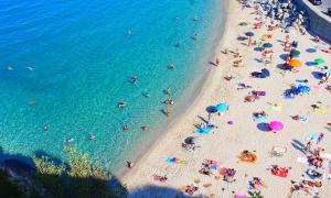 Ein Strand mit vielen Schirmen und Menschen von oben gesehen
