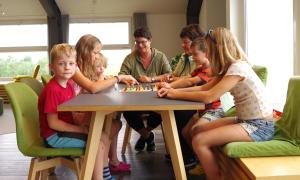Familie Demmler mit den sechs Kindern sitzen am Tisch und spielen Mensch-ärger-dich-nicht