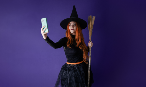 Frau dargestellt als Hexe mit Handy in der Hand, und spitzen Hut und Besen