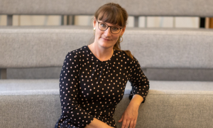 Julia Wunderlich sitzt auf einem Sessel und schaut in die Kamera.