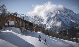 Eine Hütte im Schnee, im Hintergrund Berggipfel