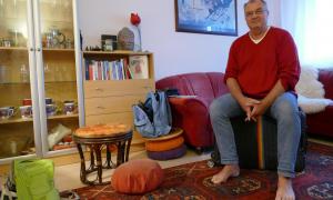 Ein Mann sitzt mit gepackten Koffern auf dem Sofa