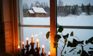 Eine orthodoxe Kirche im Schnee, durch ein Fenster gesehen, an dem Kerzen stehen