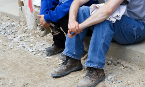 Bauarbeiter sitzen auf dem Bürgersteig und warten