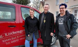 Landesbischof Christian Kopp mit dem Pfarrersehepaar Kathrin und Stefan Nagel vor dem Gemeindebus aus Bad Kötzting.