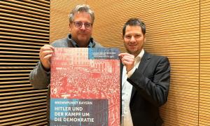 Richard Loibl (li.) und Marc Spohr im Haus der Bayerischen Geschichte Regensburg mit Plakat zur Ausstellung „Brennpunkt Bayern“ über Hitlers Aufstieg und den Nationalsozialismus.