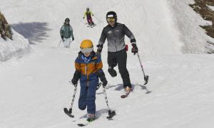 Ein Mann und ein Junge auf Skiern, beide jeweils nur mit einem Ski