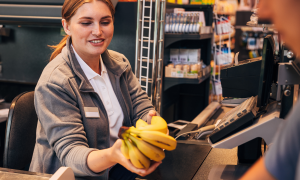 Eine Angestellte kassiert Bananen ab im Supermarkt