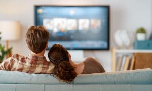 Zwei Menschen sitzen auf der Couch und schauen fern