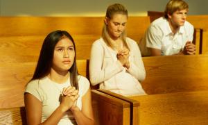 Drei junge Menschen sitzen jeweils alleine in einer Kirche