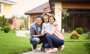 Familie im Garten ihres Hauses schaut in die Kamera. Vater, Mutter und zwei Kinder
