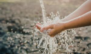 Zwei Hände fangen klares, spritzendes Wasser auf