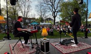 Ein Konzert unter freiem Himmel, Menschen sitzen vor einer Bühne