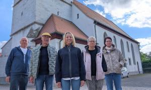Fünf Menschen stehen vor einer Kirche