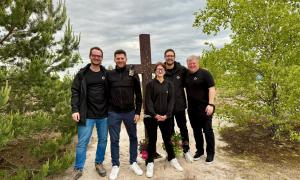 Fünf Menschen stehen vor einem Kreuz