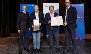 Vier Männer halten Urkunden in die Kamera