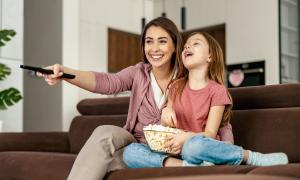 Eine Frau und ein Mädchen sitzen mit einer Schüssel Popcorn auf der Couch