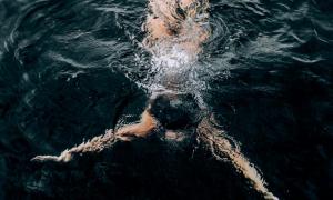 Frau schwimmt unter Wasser in dunklem Ozean
