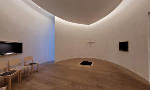 Ein halbrunder Raum mit Stühlen und einem Kreuz an der Wand