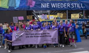Menschen in lila vor einem Schriftzug: "Nie wieder still."