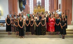 34 junge Menschen stehen in mehreren Reihen in einer Kirche