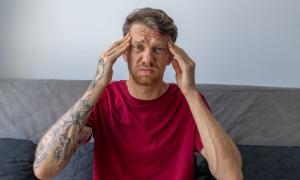 Ein Mann fasst sich mit beiden Händen an die Stirn