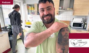 Ein Mann zeigt sein Jesus-Tattoo am Oberarm
