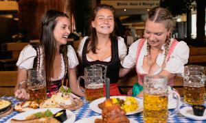 Drei Frauen in Tracht mit Bierkrügen und Essen
