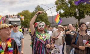 Menschen in bunter Kleidung und mit Regenbogenfahnen