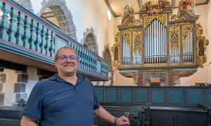 Kirchenpfleger Rainer Schülein mit der Orgel in der Kirche in Aufkirchen
