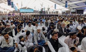 Viele Menschen in hellen Gewändern sitzen auf dem Boden
